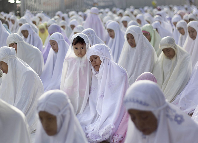 Eid begins: An Indonesian girl stands next to her mother during the Eid al Fitr prayer