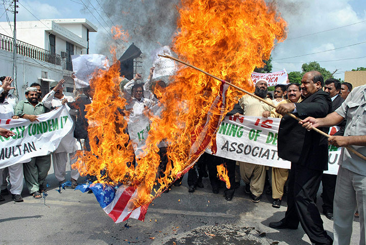 Qur'an Burning: Pakistani lawyers carry a burning US flag during a protest in Multan