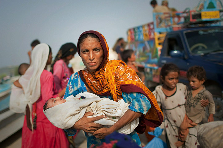 24 Hours: A woman displaced by flooding holds her baby after having been evacuated