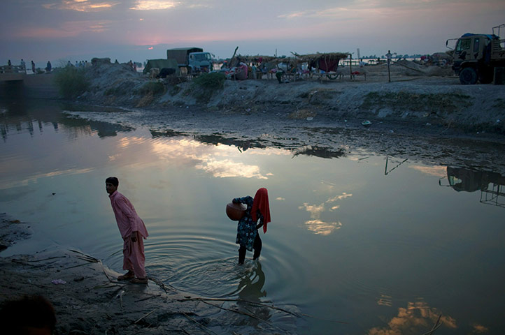 24 hours in pictures: A flood victim carries water at a relief camp in Sindh province, Pakistan