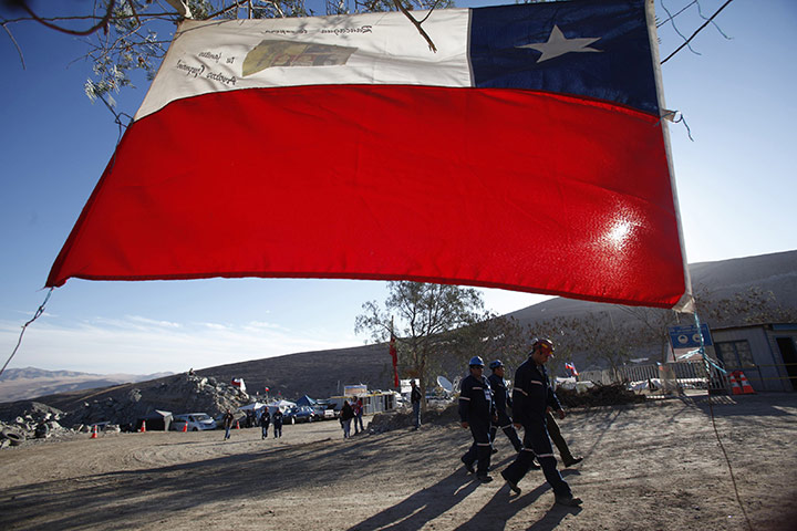 Trapped miners in Chile: 11 September: Miners walk next to a Chilean flag outside the main gate 