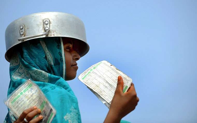 Six weeks later: Pakistan: An Internally displaced Pakistani woman puts a cooking pot on her head