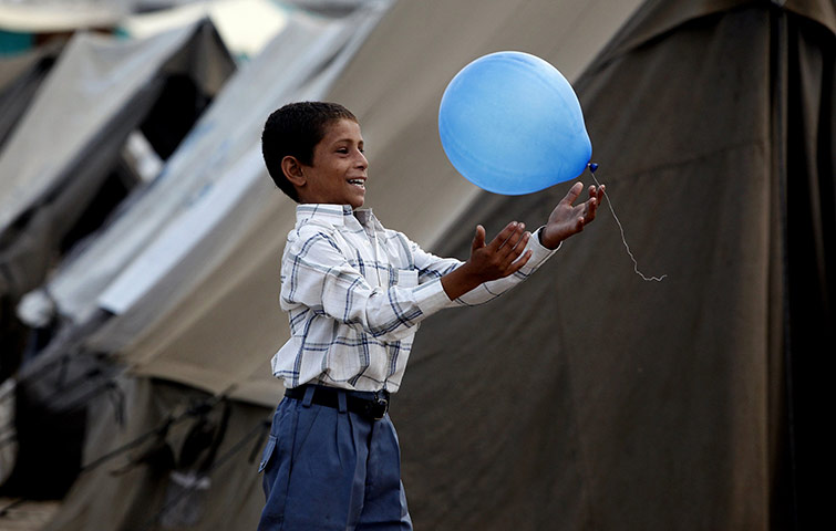 Six weeks later: Pakistan: Flood victim, wearing new clothes donated by a charity,plays with a balloon