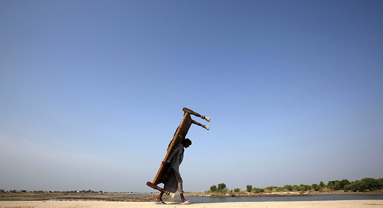 Six weeks later: Pakistan: Flood victim carries a bed on his back as he walks to his village
