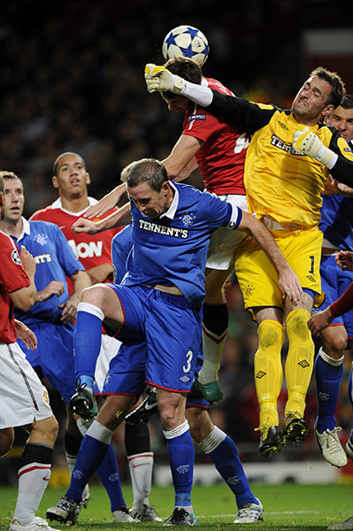 Man Utd v Rangers: Allan McGregor punches clear at a corner under pressure from Jonny Evans