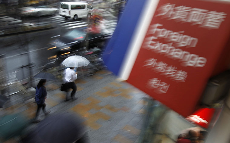 Week in Business: People walk past an exchange booth in Tokyo, Japan