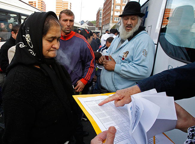 Roma Return : Immgration officer checks list as Roma families wait to board a bus