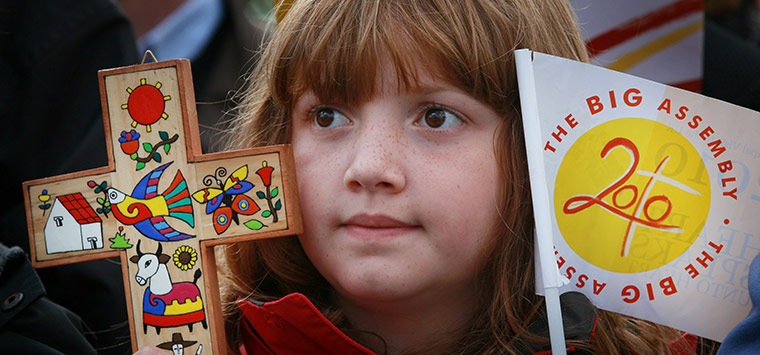 Pope 3: A school girl holds a decorated crucifix and a Papal flag 