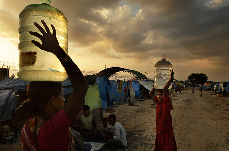 Commonwealth Games Labour: A family carries drinking water to workers near a Commonwealth Games depot