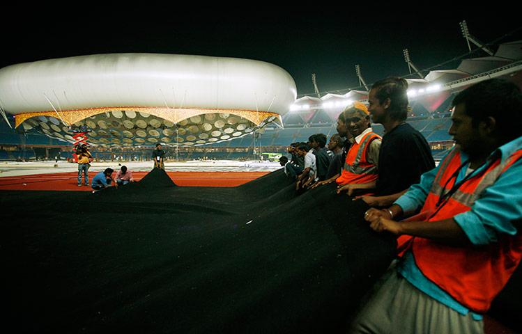 Commonwealth Games Labour: Workers shift a ground cover at the Jawaharlal Nehru Stadium