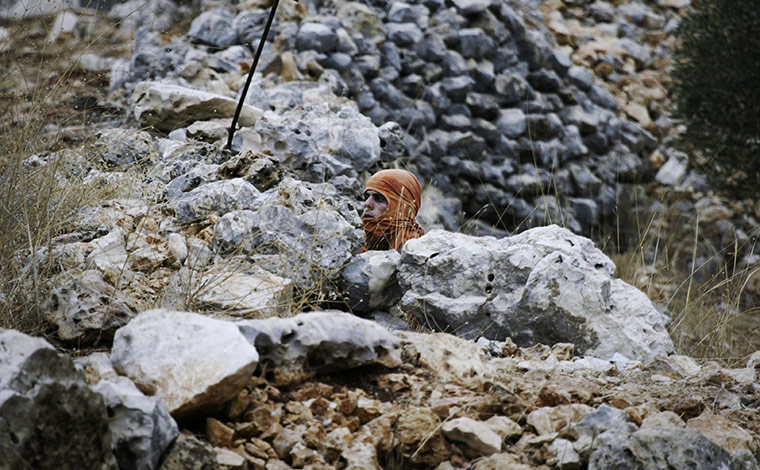 24 Hours in Pictures: A Palestinian stones-thrower hides while watching Israeli troops