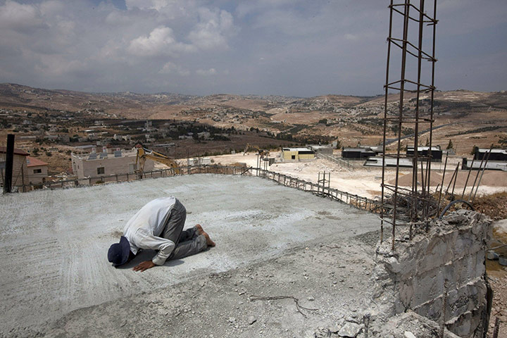 Middle East Peace Talks: A Palestinian laborer prays as he takes a break from work in the West Bank