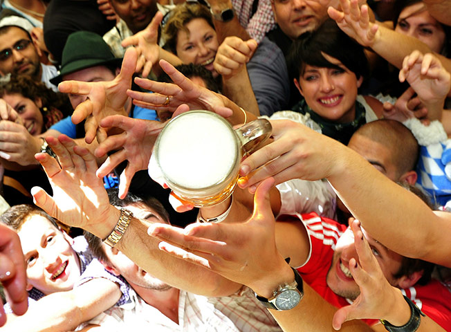 Oktoberfest in Munich: Revellers reach out to get a one-litre mug of beer in the Hofbrauhaus tent