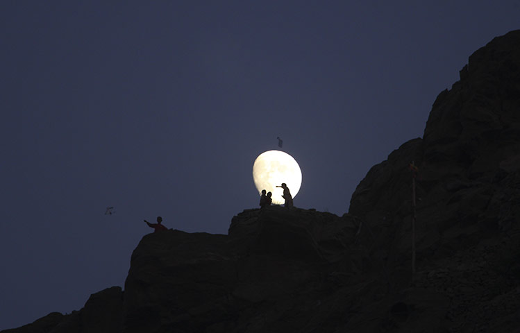 24 hours in pictures: Kabul, Afghanistan: Children fly kites on a hillside as the moon rises