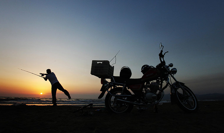 24 hours in pictures: A man fishes near his motorcycle on Pamucak Beach, Turkey