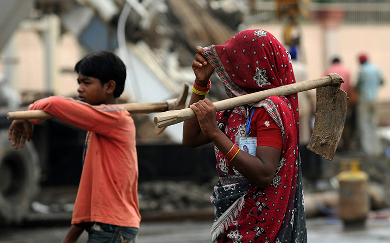 Commonwealth games: Indian labourers walk past the entrance Jawaharlal Nehru Stadium