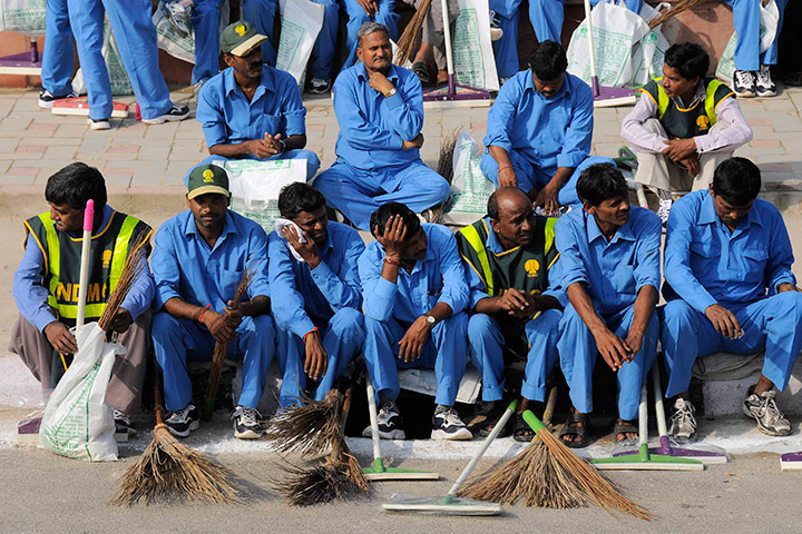 Commonwealth Games Clean: Workers sit on a pavement before entering the athletes village