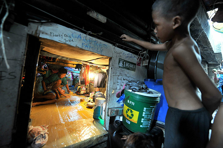 24 Hours:  A boy stands watching a woman in a shanty under a bridge in Manila