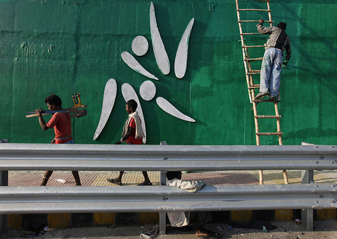 Commonwealth games: Indian workers paint a wall near the Jawaharlal Nehru Stadium