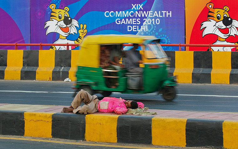 Commonwealth games: An Indian man sleeps on the middle strip of the road 