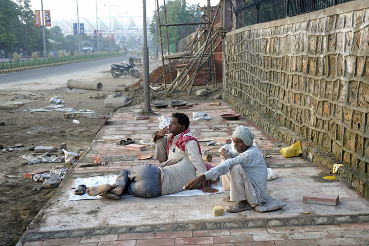 Commonwealth games: Indian labourers smoke bidis (local cigars) on the semi-finished pavement