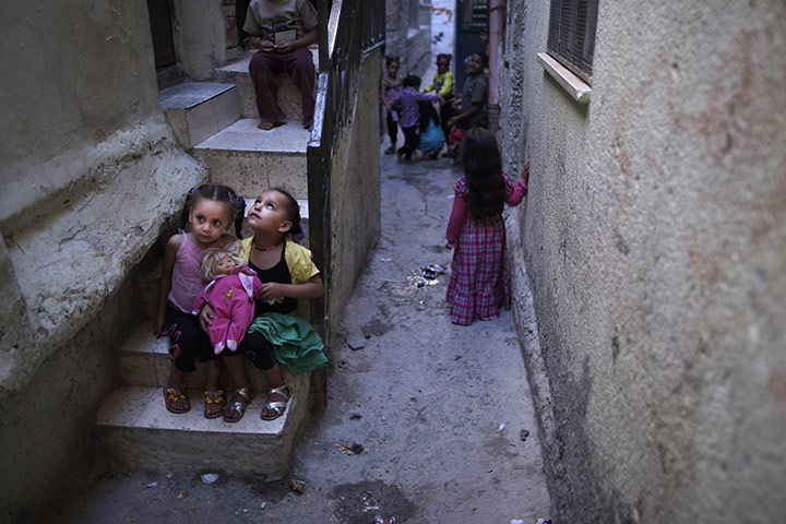 Muhammed Muheisen: Palestinian girls play with a doll while sitting in front of a house