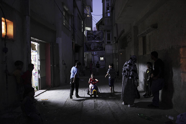Muhammed Muheisen: Palestinians gather in an alley of Al-Amari refugee 