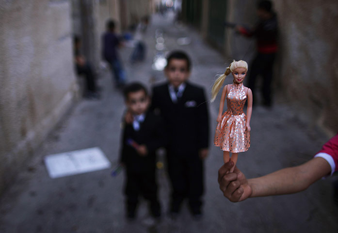 Muhammed Muheisen: A Palestinian girl shows her toy while playing in an alley 