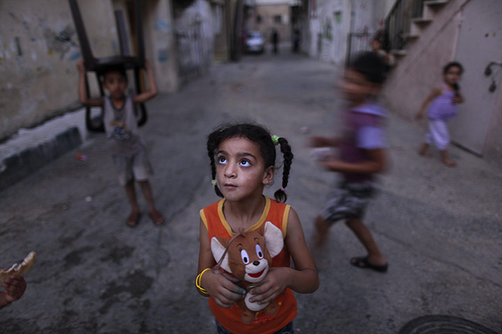 Muhammed Muheisen: A Palestinian girl holds her toy as she hears her mother calling her