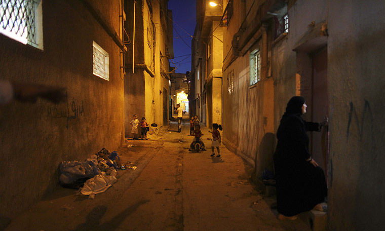 Muhammed Muheisen: A Palestinian woman talks with her neighbor as children play