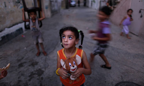 A Palestinian girl holds her toy as she hears her mother