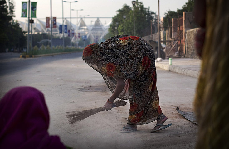 24 hours: A woman sweeps the street outside Jawaharlal Nehru Stadium