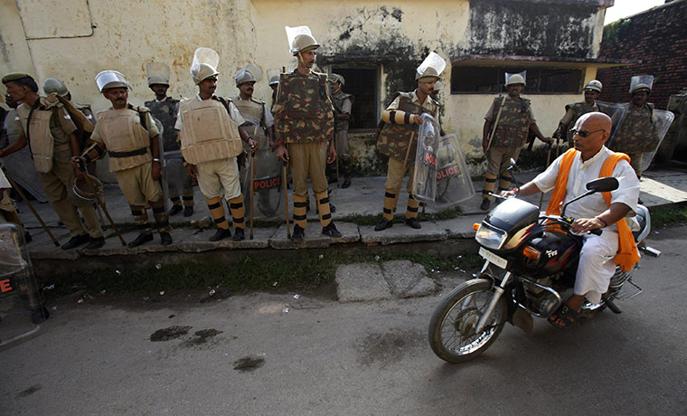 Ayodhya dispute: A Hindu holy man rides a motorcycle as policemen stand guard on a street