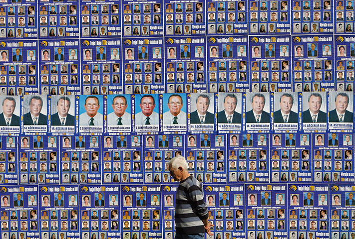 24hours Wed: A man walks with posters for parliamentary elections in Sarajevo