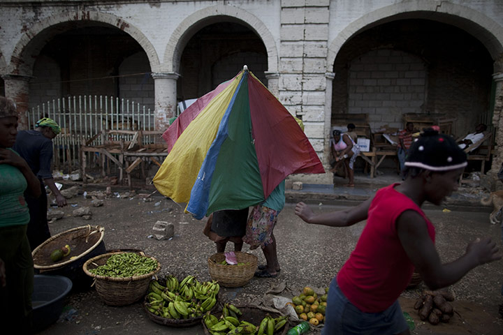 24hours Wed: Women use an umbrella to shield themselves from rain in Haiti