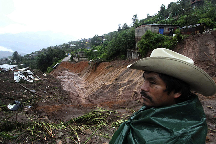 Mexico mudslides: A man stands in front of damage left after a landslide in Tlahuitoltepec