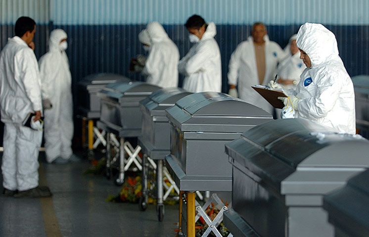 Mexico drug war: Forensic experts inspect the coffins containing the remains of 16 Honduran