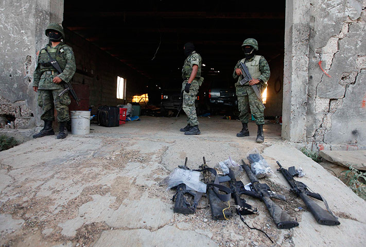 Mexico drug war: Soldiers stand next to weapons seized at a warehouse after a gunfight