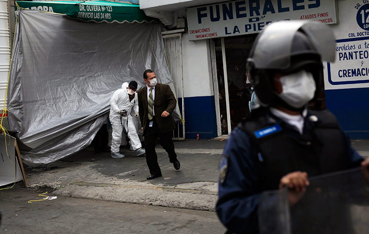 Mexico drug war: A Mexican police officer stands guard outside a mortuary in Mexico City