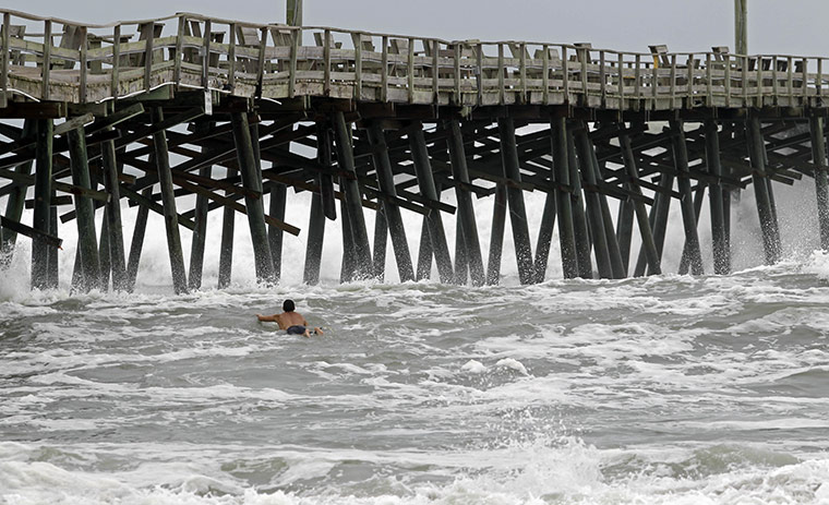 24 Hours: A surfer battles the waves near a pier as Hurricane Earl approaches