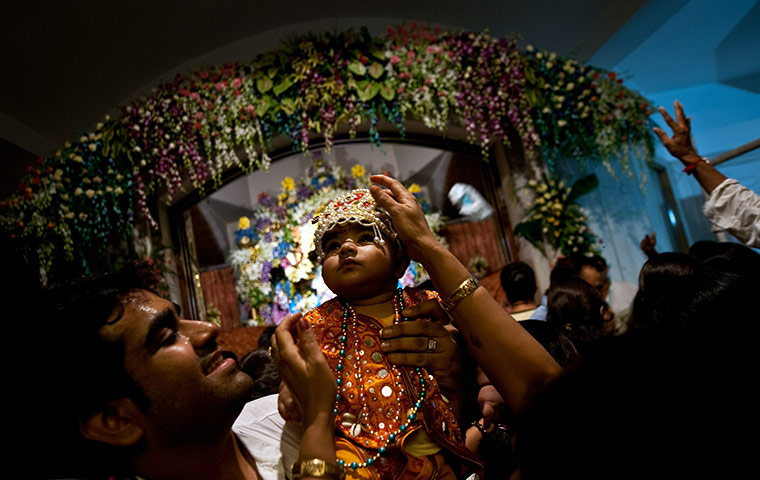 24 Hours: Indian Hindu man holds his son dressed as Lord Krishna at the ISKCON temple