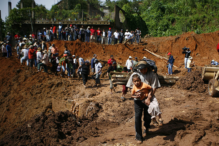 Mexico landslides: A man carries a child after a landslide in Santa Maria de Tlahuitoltepec