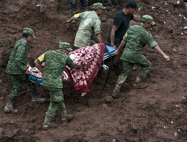 Mexico landslides: Rescue workers carry a corpse on a stretcher after a landslide