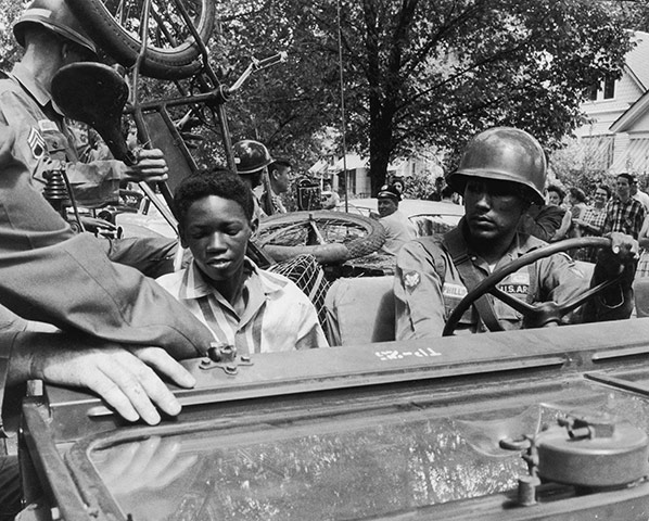 Little Rock: National Guardsmen give a black student and his bicycle a lift to school