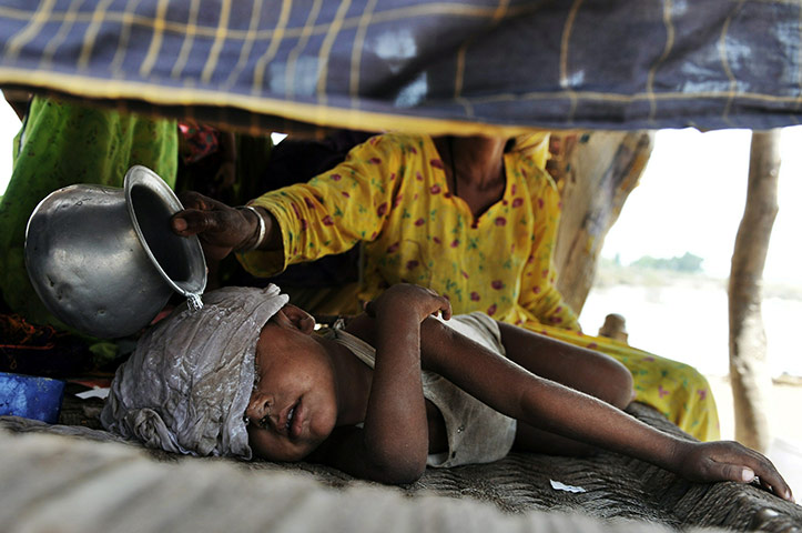 Pakistan Flooding Update: A desperate Pakistani woman displaced by floods tends her sons fever