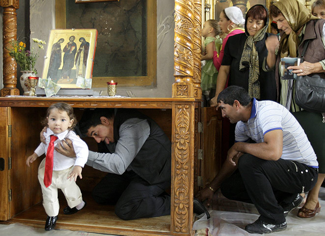 Roma celebrations: A Romanian Roma man goes under a table with a baby 