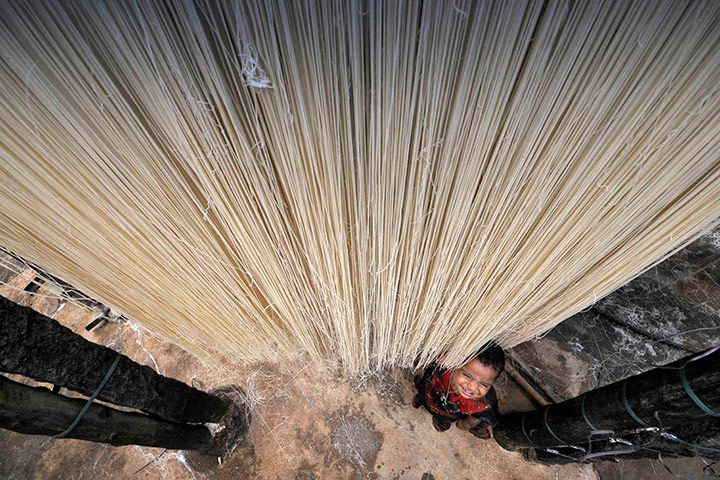 24 hours in pics: A child playing with strands of vermicelli hung for drying