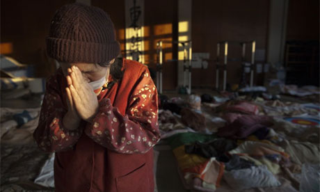 A woman prays at a rescue centre in Kesennuma, Japan, where a tsunami survivor has been found and pulled from the rubble after eight days