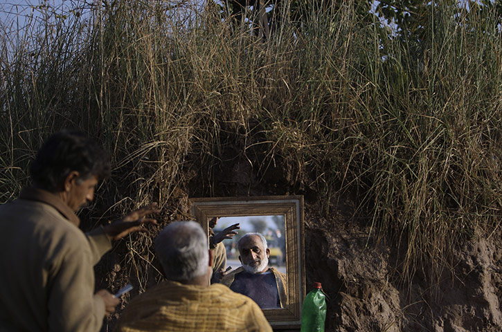 24 Hours in Pics: A man is reflected in a street barber's mirror near Islamabad