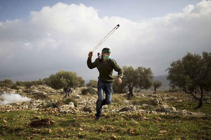 24 Hours in Pics: A Palestinian protester uses a slingshot to throw stones at Israeli troops